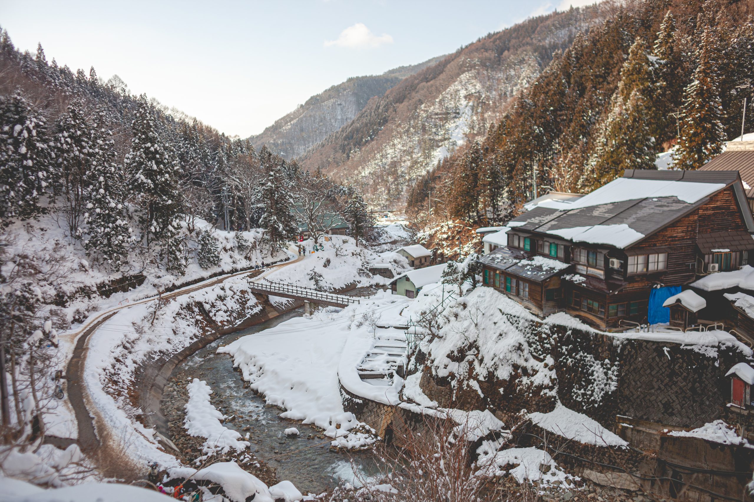 high angle shot wooden house surrounded by forested mountain covered snow winter scaled
